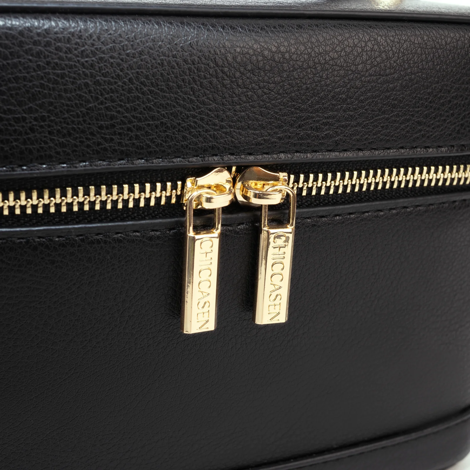 Jet Black CHICCASEN Vanity Case showing the microfibre faux-leather grain, stitching and gold-tone double zip pulls.